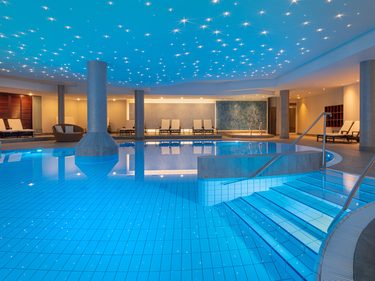 Innenpool im Wellnessbereich mit Sternenhimmel-Decke, Einstiegstreppe, Säulen und Ruheliegen.
