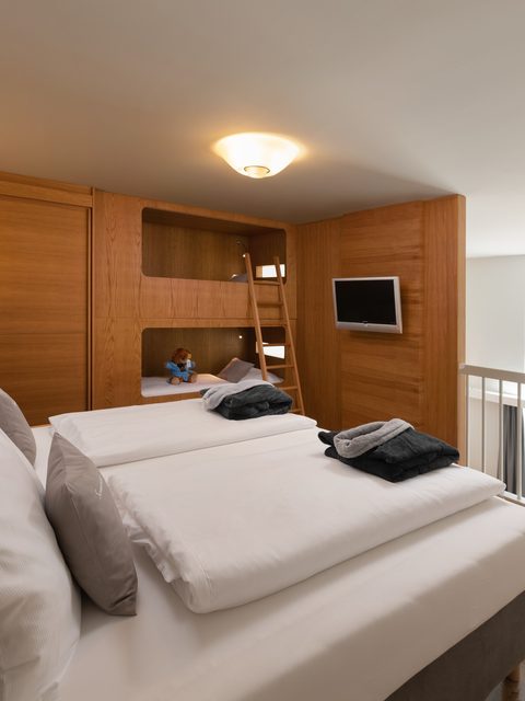 Familienzimmer mit Doppelbett, Holzhochbett, Leiter, Fernseher und Galerie mit Fenster.