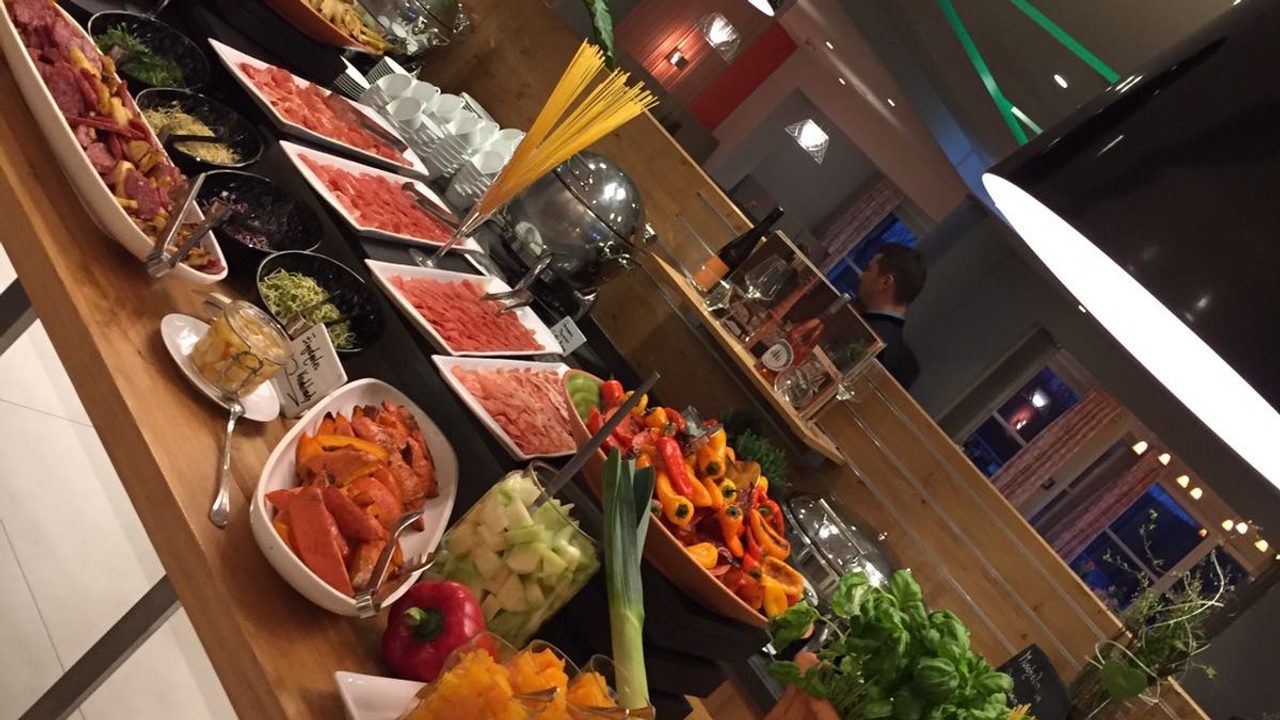 Buffet im Restaurant mit Vorspeisen, Gemüse, Kräutern und verschiedenen kalten Speisen unter Wärmelampen.