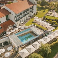 Luftaufnahme eines Hotels mit Außenpool, Sonnenterrasse, Garten und Liegebereichen.
